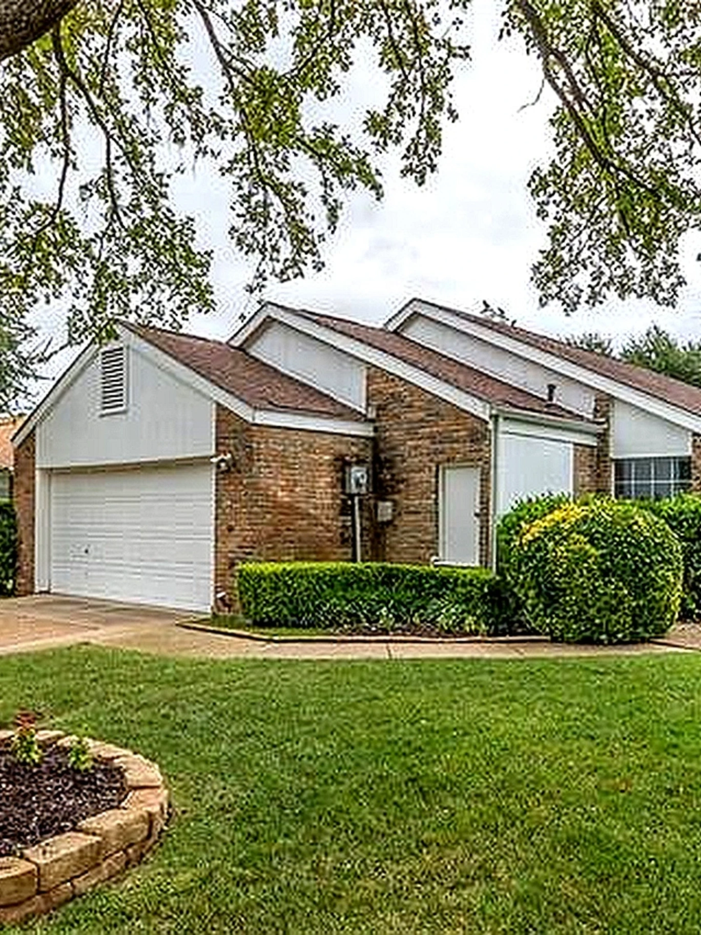 Single-family brick home with shingle roof and landscaped yard in Addison, Dallas County, TX