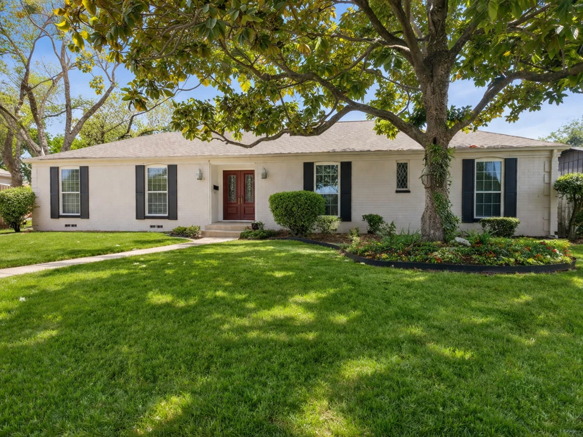 White painted brick ranch home with shingle roof, dark shutters, and mature magnolia tree on Shadywood Lane in Richardson, TX