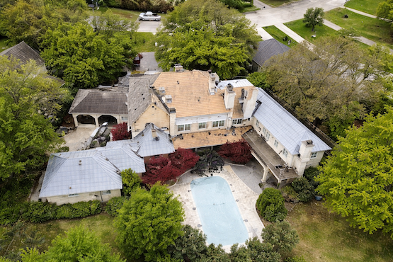 Aerial view of a large home with pool in Plano, TX before new roof installation, showing roof stripped and prepped for replacement