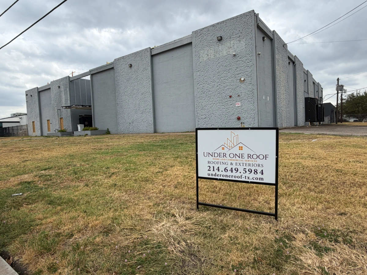 Under One Roof yard sign in front of a commercial building undergoing roof replacement in Dallas, Dallas County, TX.