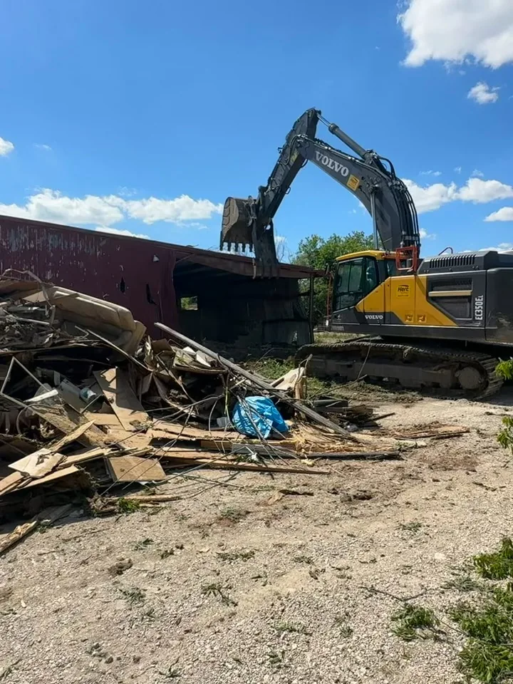 Commercial Demolition Farmers Branch: Excavator next to a long brick commercial building coming down Excavator next to a long brick commercial building coming down