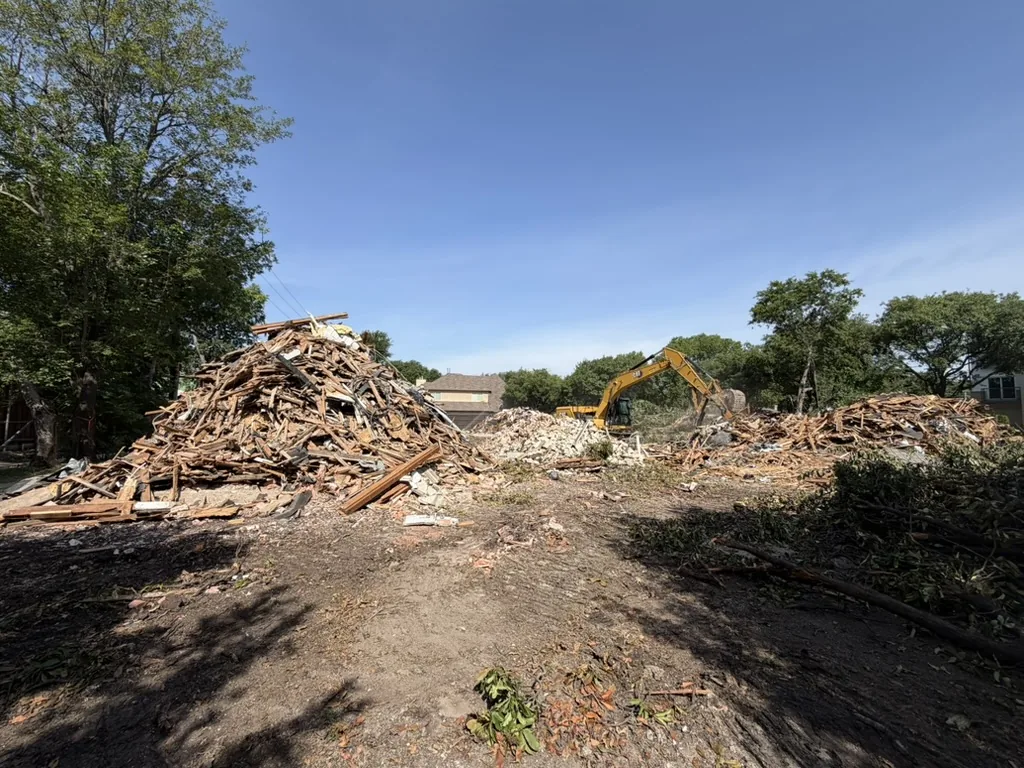 Excavator behind a pile of debris during a residential demolition in Dallas
