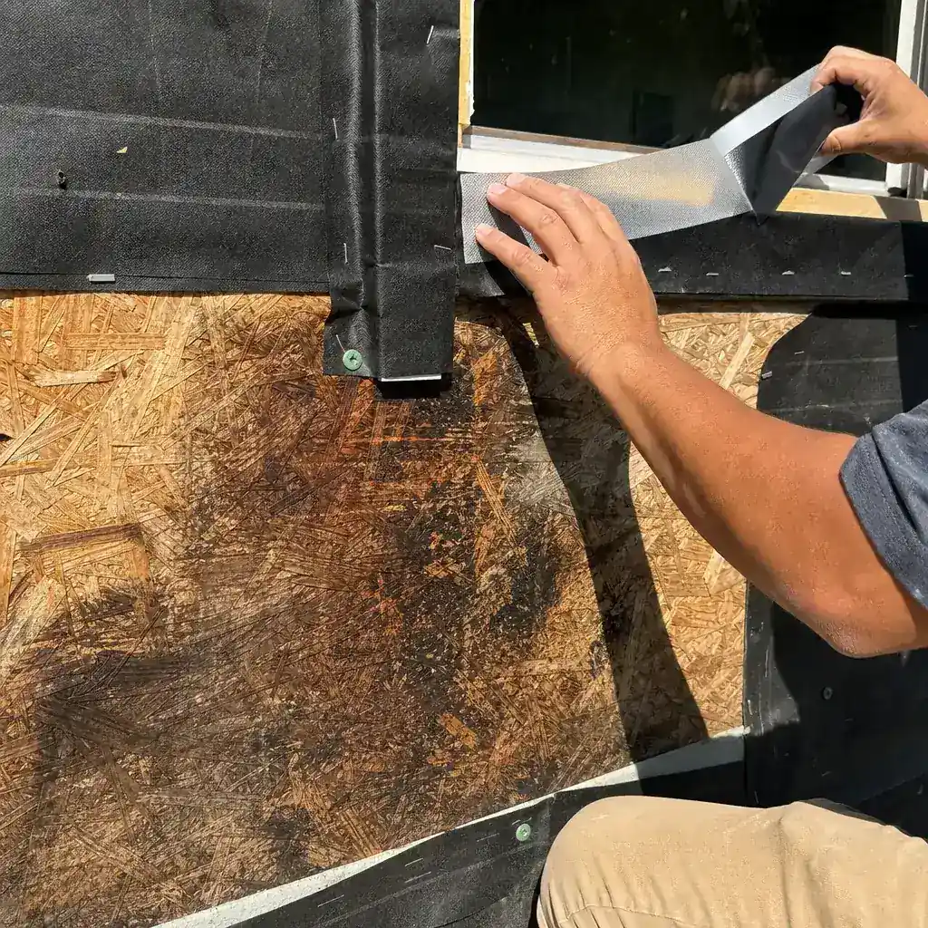 Exposed house wrap and window flashing beneath removed siding panels on a Farmers Branch home