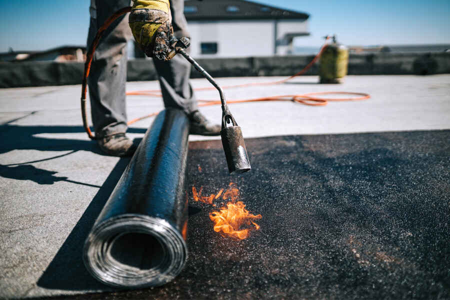Roofer performing flat roof repair on commercial property in Addison, Dallas County, TX.