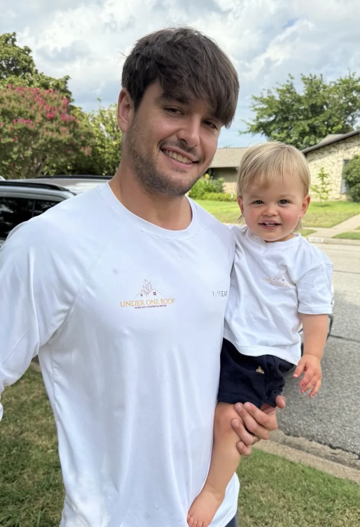Max Wensinger, owner of Under One Roof, holding his son outside a job site in Farmers Branch, Dallas County, TX