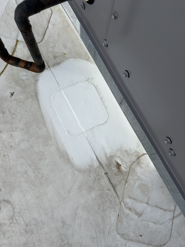 TPO roof repair showing a white patch and existing sealant on a commercial flat roof in Plano, Collin County, TX.