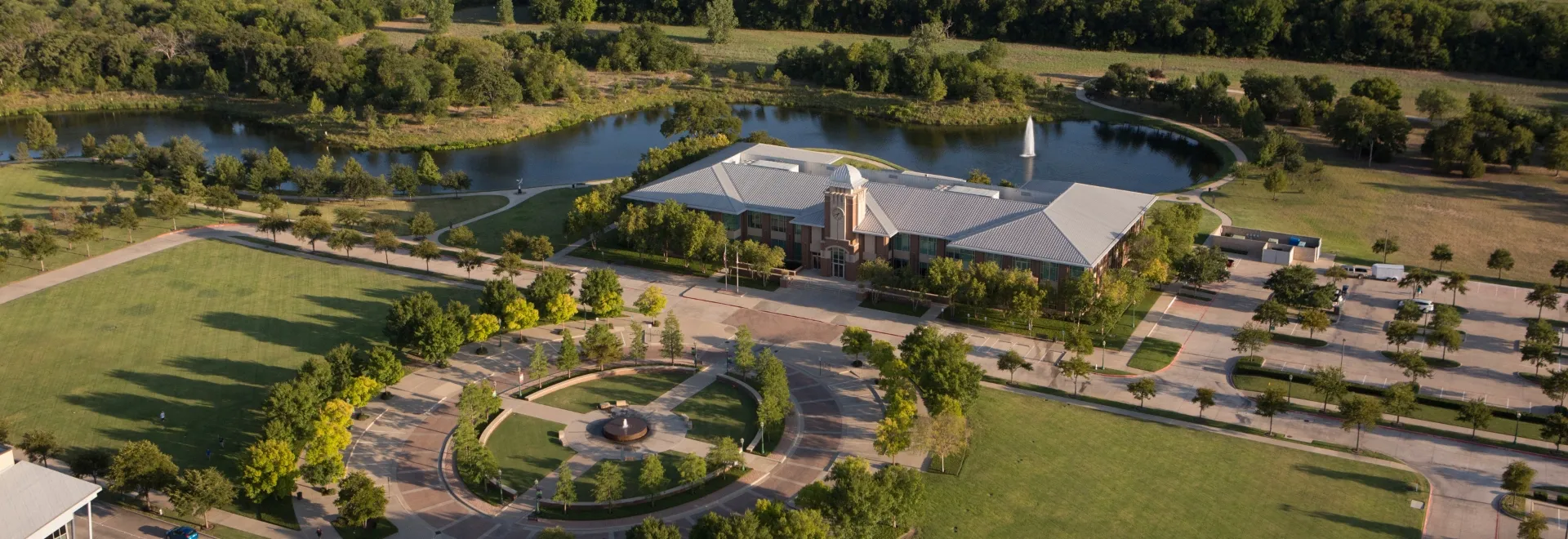 Aerial view of Keller Texas town center with beautiful landscaping, pond, and modern architecture representing the premium community served by Under One Roof home services
