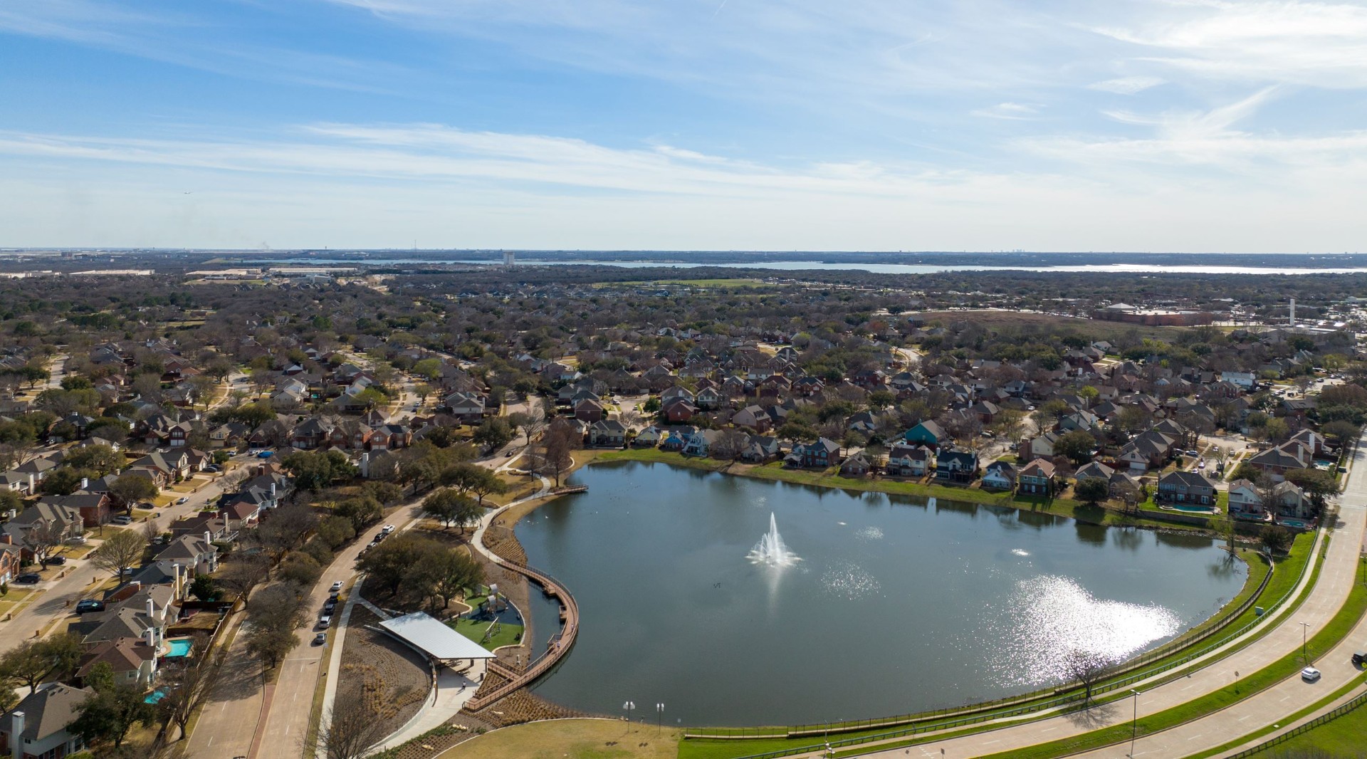Flower Mound Texas aerial view of scenic lakefront community with fountain centerpiece surrounded by beautiful residential neighborhoods and tree-lined streets - Under One Roof roofing and home services coverage area