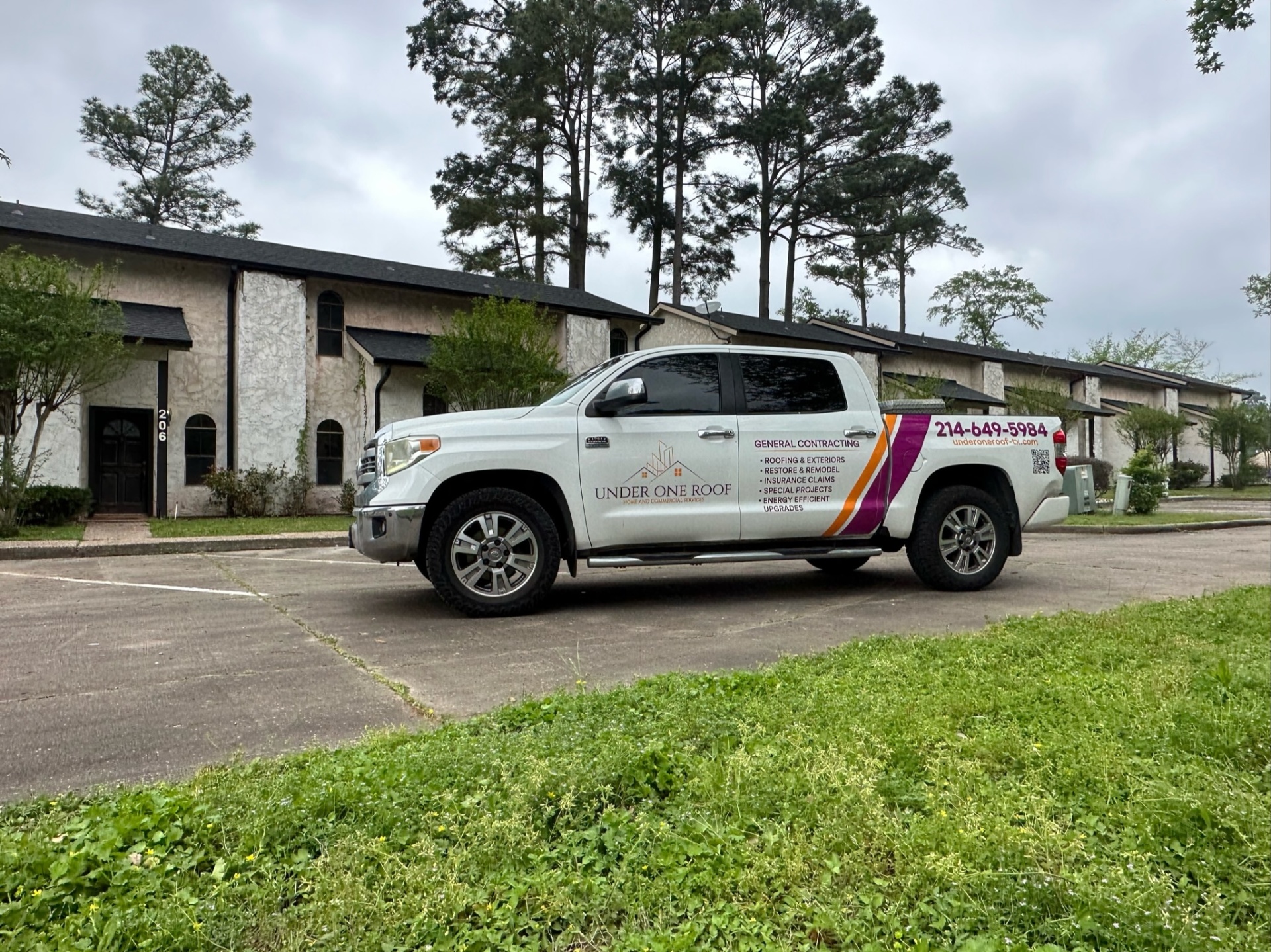 Under One Roof service truck parked in front of multi-unit residential buildings in Dallas, Texas, showcasing professional roofing services for townhouses and apartment complexes
