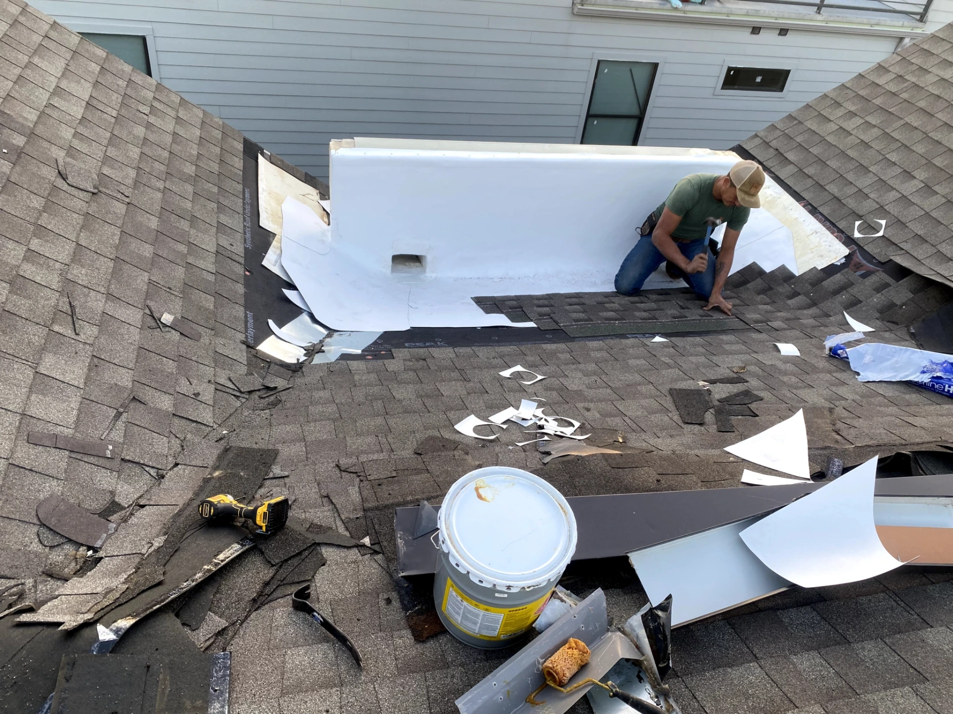 Technician performing townhouse roof repair on dark shingles in the Medical Distrct in Dallas, TX by Under One Roof